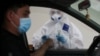 Almaty, Kazakhstan - A health worker approaches a car driver at a mobile testing station for the coronavirus disease (COVID-19)